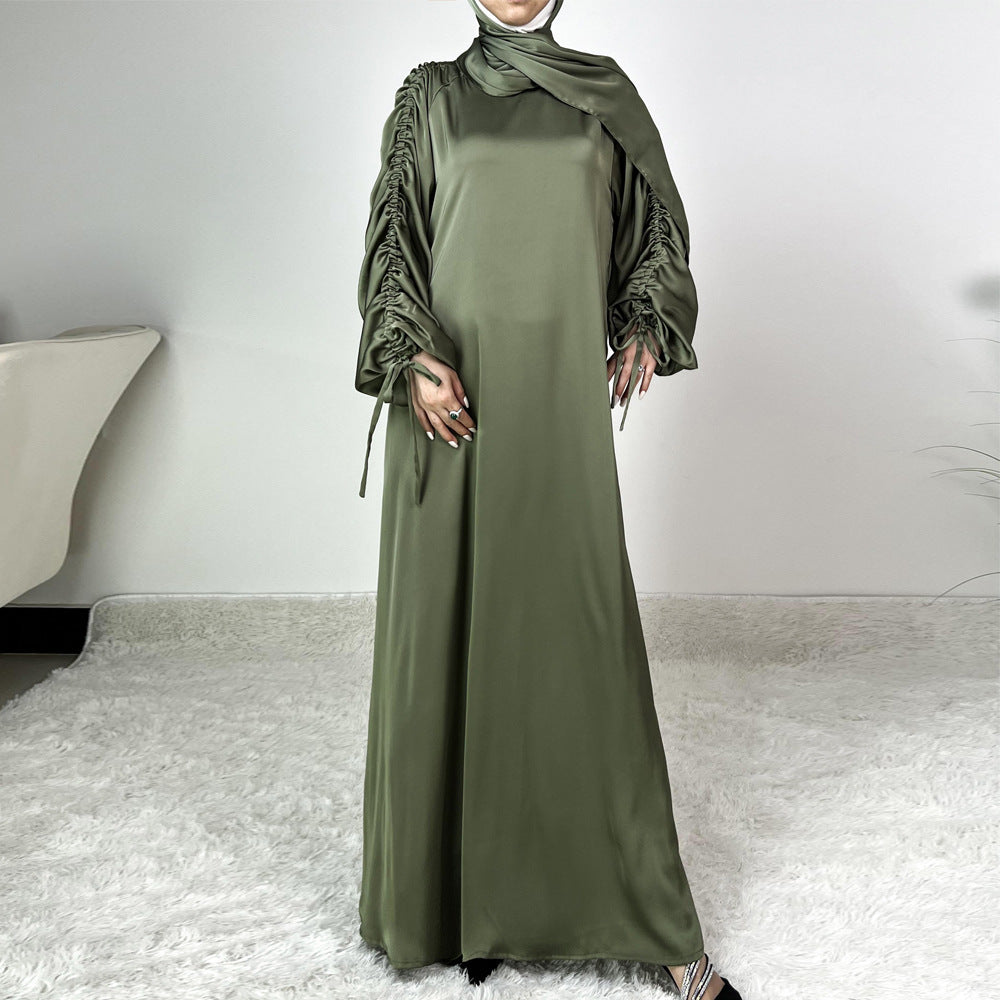 Élégance satinée, féminité affirmée. Cette abaya en tissu satiné ultra chic met en valeur la silhouette avec des manches froncées modernes et une finition fluide