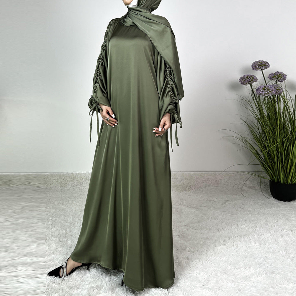 Élégance satinée, féminité affirmée. Cette abaya en tissu satiné ultra chic met en valeur la silhouette avec des manches froncées modernes et une finition fluide